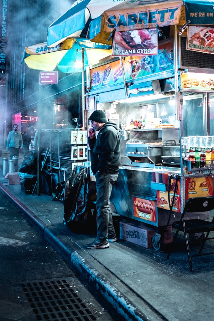Street food stall in NYC at night with a vendor in winter attire.